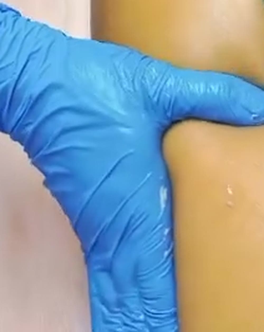 Mãos da Mari trabalhando a perna, de perto.